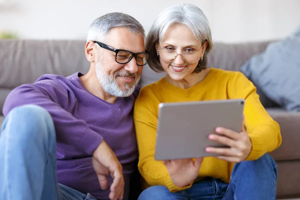 Hermosa pareja de familia madura mirando a la tableta con sonrisa en la cara mientras pasan tiempo juntos — Foto de Stock