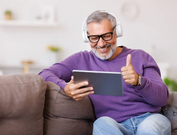 Guapo feliz hombre mayor saludando a mano mientras habla en línea en la tableta digital con la familia —  Fotos de Stock