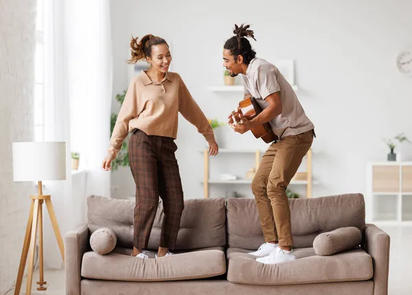 Young funny happy african american couple playing guitar and dancing at home on weekend — Stock Photo, Image