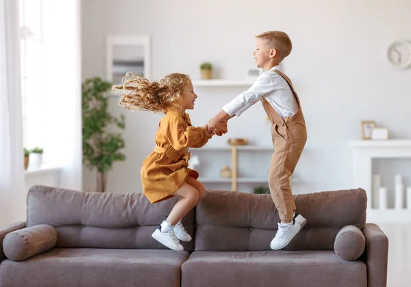 Petits enfants heureux frère et sœur sautant sur le canapé à la maison — Photo