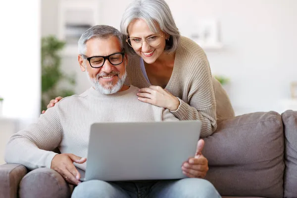 Heureux couple de personnes âgées regardant la comédie ou drôle de vidéo sur ordinateur portable tout en passant du temps libre à la maison — Photo