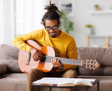 Kağıt üzerinde klasik akustik gitar okuma notalarıyla odaklanmış Afro-Amerikan erkek müzisyen.