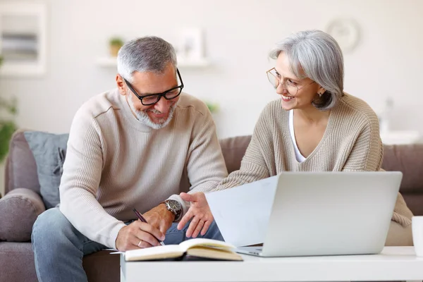 Χαμογελαστό ηλικιωμένο ζευγάρι διαβάζει επιστολή κοινοποίησης με καλά νέα από την τράπεζα, ενώ κάθεται με φορητό υπολογιστή — Φωτογραφία Αρχείου