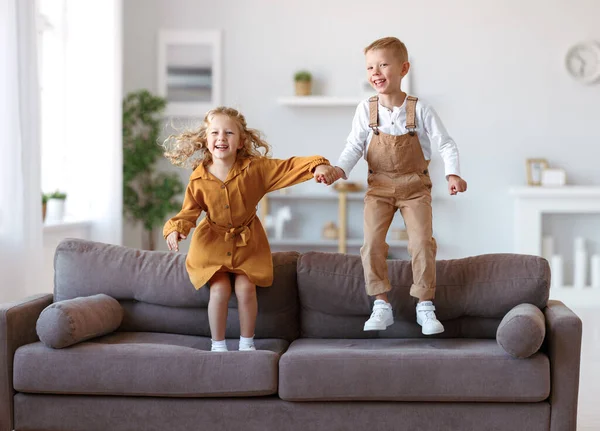 Overgelukkig kleine kinderen broer en zus springen op de bank thuis — Stockfoto