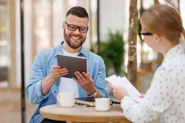 Satisfied man and woman discussing new business strategy during meeting in outdoor cafe — Stock Photo, Image