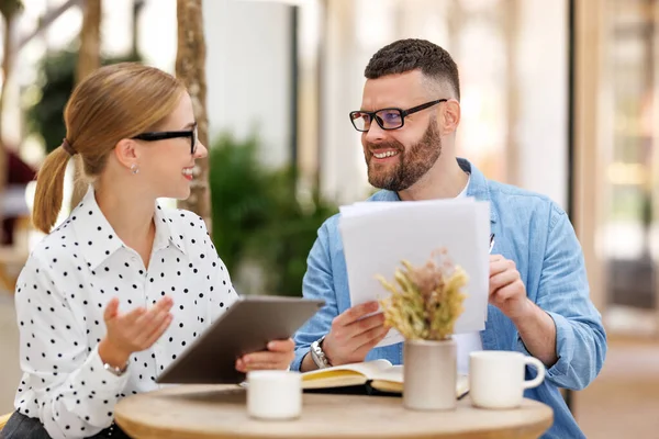 Two smiling business colleagues young man and woman working together on project at outdoor cafe — Stock Photo, Image