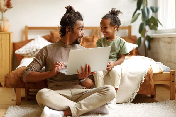 Щаслива афро-американська сім'я маленький син з татом дивляться смішні відео на ноутбуці разом вдома. — стокове фото
