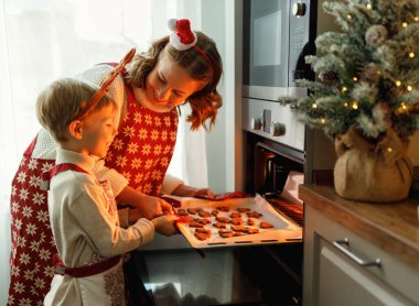 Mutlu aile anne ve oğlu fırından taze pişmiş Noel kurabiyeleri alıyor.