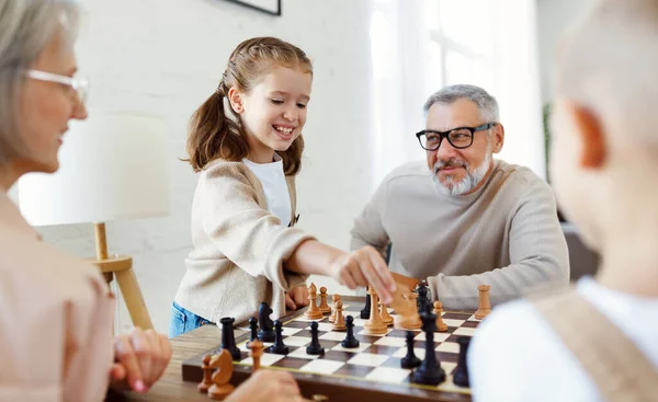 Geschwister spielen Schach, während sie mit den Großeltern im Wohnzimmer sitzen — Stockfoto