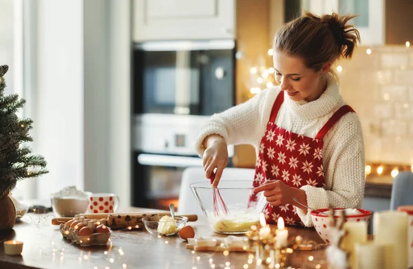 Jonge glimlachende mooie vrouw in schort maken deeg voor kerst peperkoek koekjes in de keuken — Stockfoto
