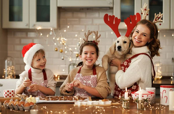 Gelukkige familie moeder, twee kinderen met hond golden retriever in de keuken, het bereiden van kerstkoekjes — Stockfoto