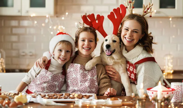 Gelukkige familie moeder, twee kinderen met hond golden retriever in de keuken, het bereiden van kerstkoekjes — Stockfoto