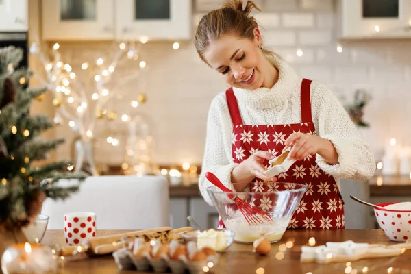 Joven sonriente hermosa mujer en delantal haciendo masa para Navidad galletas de jengibre en la cocina — Foto de Stock