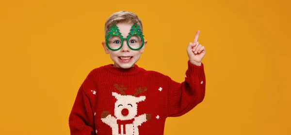 Lächelnder kleiner Junge mit lustiger Brille in Form von Weihnachtsbäumen, der mit dem Finger auf den Kopf zeigt — Stockfoto