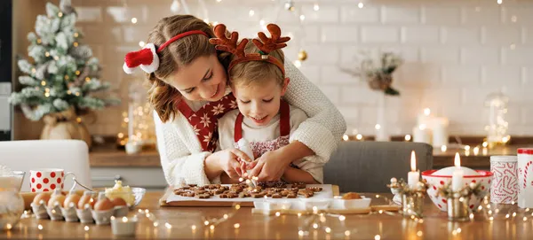 Boldog család anya és fia kötényben, akik otthon készítik a karácsonyi sütiket. — Stock Fotó