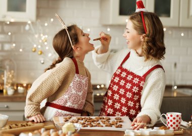 Neşeli, mutlu bir aile annesi ve kızı mutfakta Noel kurabiyesi pişirirken eğleniyorlar.