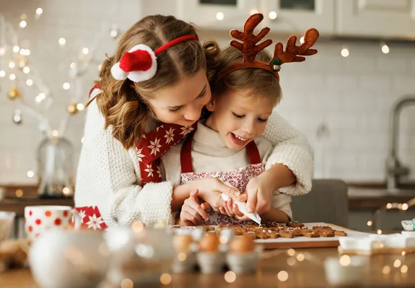 Gelukkig familie moeder en zoon in schorten het maken van kerstkoekjes samen thuis — Stockfoto