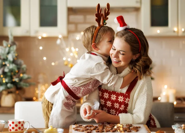 Liefdevolle moeder en jongen zoon knuffelen omarmen terwijl Kerstmis koekjes in de keuken op Kerstmis — Stockfoto
