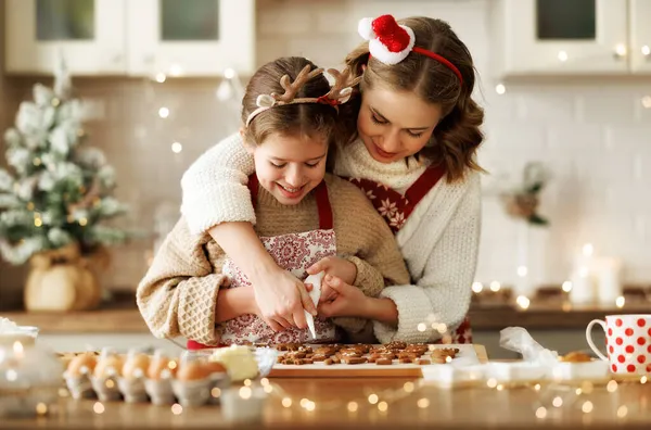 Feliz familia madre y niña hija decorando galletas de jengibre de Navidad después de hornear — Foto de Stock