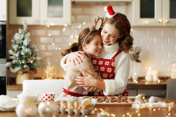 Madre y niña cariñosa hija abrazándose abrazando mientras que las galletas de Navidad en la cocina en Navidad — Foto de Stock