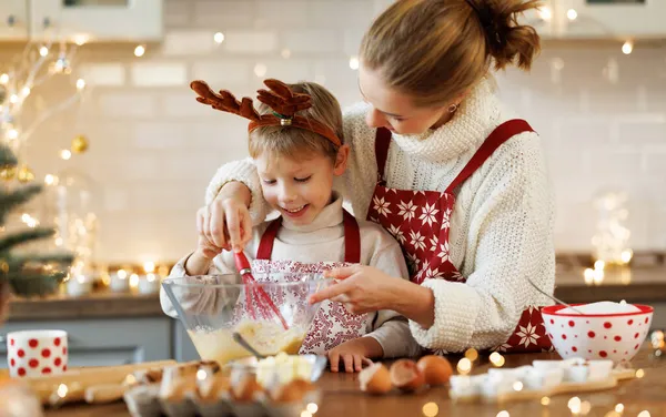 Schattige kleine zoon jongen helpen moeder om deeg te maken voor kerst koekjes in gezellige keuken thuis — Stockfoto