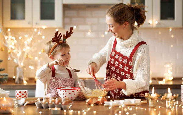 Lindo niño pequeño ayudando a la madre a hacer masa para galletas de Navidad en la acogedora cocina en casa — Foto de Stock