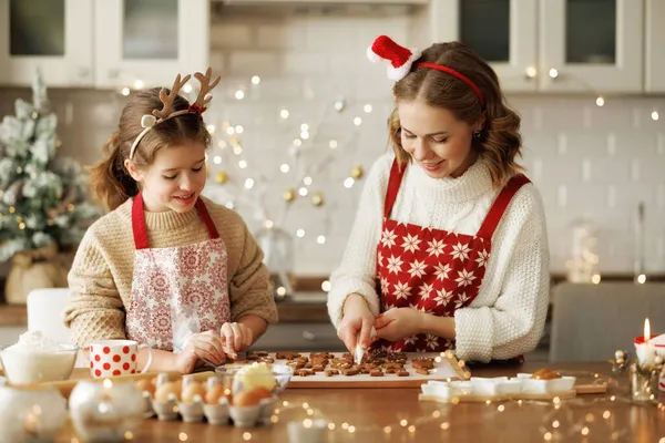 Família feliz mãe e menina filha decorando biscoitos de gengibre de Natal após o cozimento — Fotografia de Stock