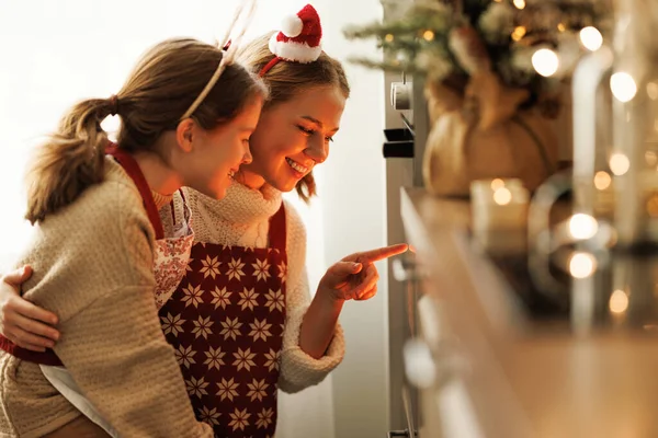 Família de carinho feliz mãe e filha esperando pela preparação de biscoitos de Natal no forno — Fotografia de Stock