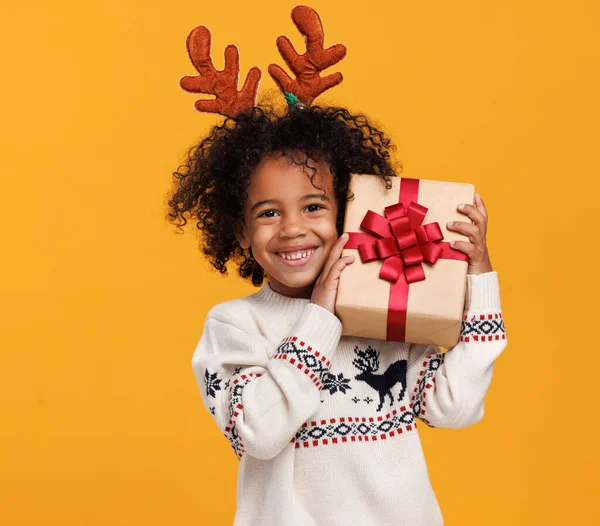 Vacanze di Natale. Felice piccolo ragazzo africano americano che indossa corna di cervo rosso con scatola regalo di Natale — Foto Stock