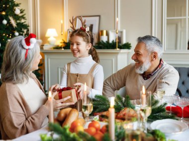 Küçük kız torun Noel hediyesi veriyor. Noel yemeği sırasında büyükanneye sürpriz yapıyor.