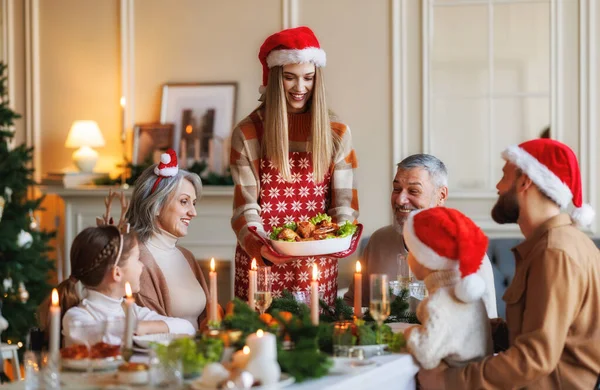 Feliz gran familia en los sombreros de Santa celebrando la Navidad en casa, disfrutando de la cena de Navidad festiva —  Fotos de Stock