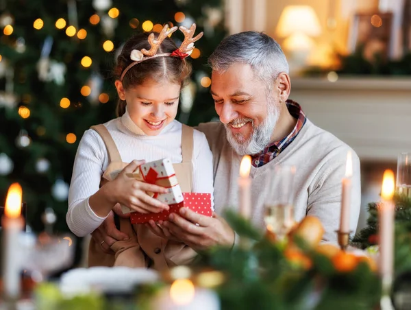 Großvater mit aufgeregter Enkelin beim Auspacken der Weihnachtsgeschenkbox neben geschmücktem Weihnachtsbaum — Stockfoto