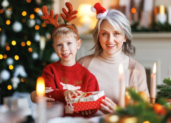 Mormor med upphetsad flicka sonson packa upp julklapp låda nära dekorerad xmas träd — Stockfoto