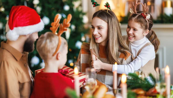 Une famille heureuse avec deux enfants célèbre Noël à la maison, parents et enfants échangeant des cadeaux de Noël — Photo