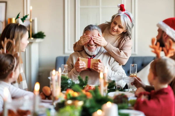 Familia hacer sorpresa para el abuelo feliz en Navidad, mujer mayor da regalo de Navidad al marido — Foto de Stock