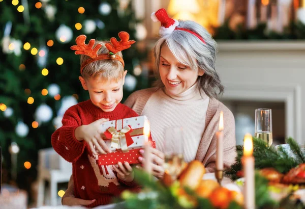 Großmutter mit aufgeregtem Enkelkind beim Auspacken der Weihnachtsgeschenkbox neben geschmücktem Weihnachtsbaum — Stockfoto