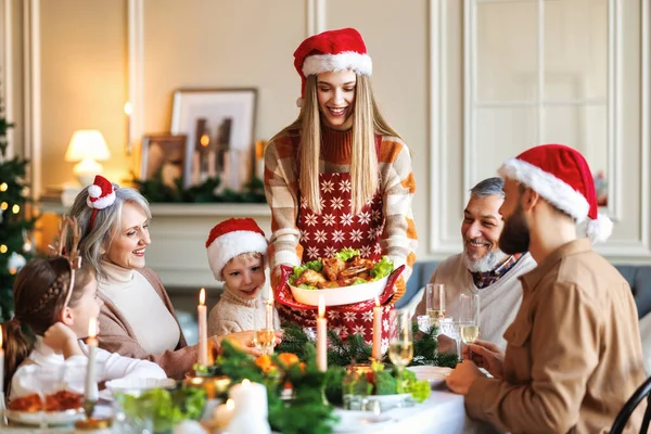Feliz gran familia en los sombreros de Santa celebrando la Navidad en casa, disfrutando de la cena de Navidad festiva — Foto de Stock