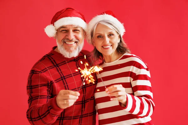 Feliz alegre pareja de la familia de ancianos en los sombreros de Santa con bengala sparkler luz celebrar Año Nuevo —  Fotos de Stock