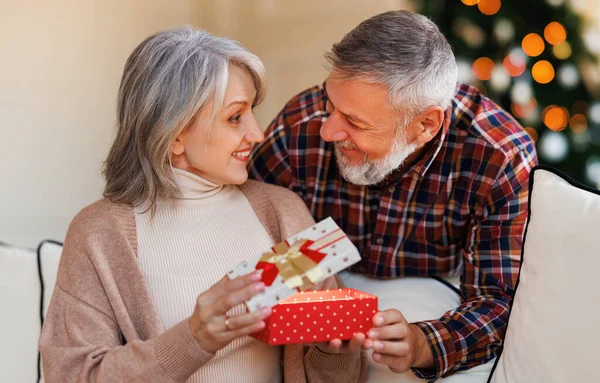 Kochający starszy mąż daje prezent świąteczny pudełko szczęśliwej zaskoczonej żony — Zdjęcie stockowe