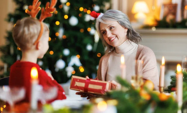 Menino neto dando embrulhado presente de Natal à avó sorridente durante as férias de inverno — Fotografia de Stock