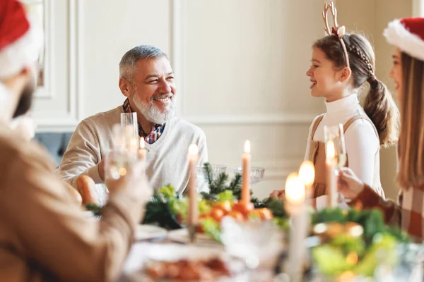 Feliz familia multi generación en los sombreros de Santa en la mesa de la cena, diciendo brindis de Navidad y tintineo vasos — Foto de Stock