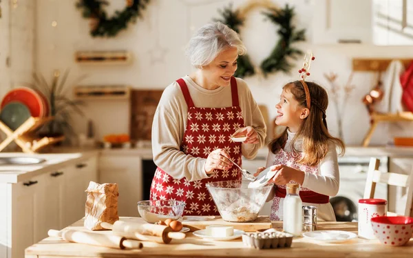 Schattig klein meisje helpen senior oma om deeg te maken voor traditionele kerstkoekjes — Stockfoto