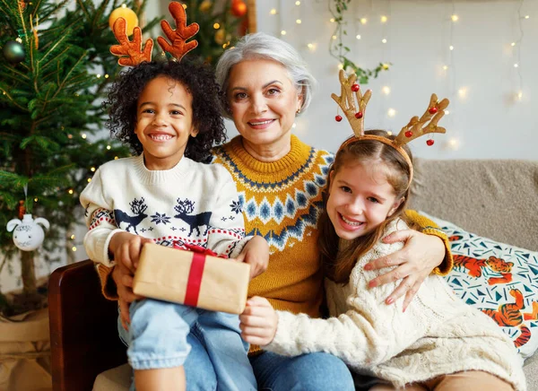 Heureuse grand-mère aînée de la famille multiraciale avec des enfants multiraciaux mignons le matin de Noël à la maison — Photo