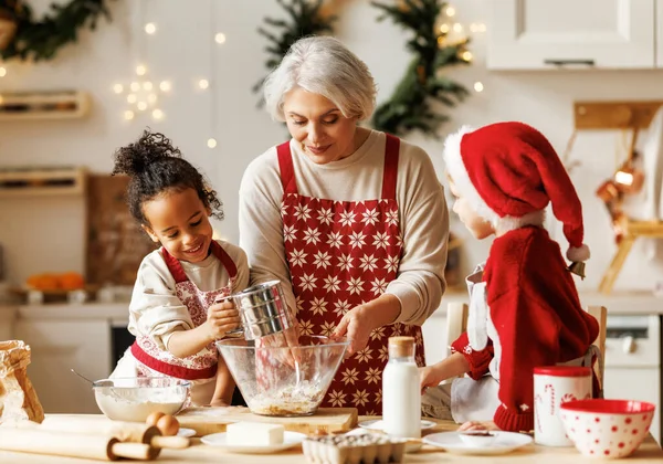 Glückliche multiethnische Kinder helfen Großmutter beim Kochen von Weihnachtsplätzchen in der Küche während der Winterferien — Stockfoto