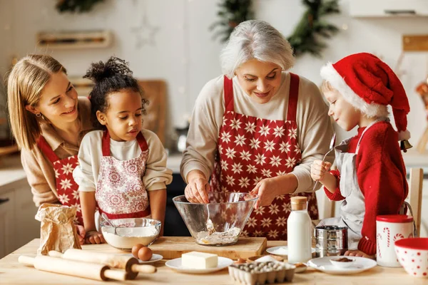 Χαρούμενη πολυεθνική οικογένεια, γιαγιά, μητέρα και παιδιά να μαγειρεύουν μαζί τα Χριστούγεννα στην κουζίνα — Φωτογραφία Αρχείου