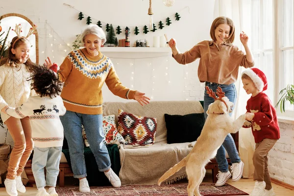 Ευτυχισμένη πολυφυλετική οικογένεια με τρία παιδιά και golden retriever να διασκεδάσουν την ημέρα των Χριστουγέννων στο σπίτι — Φωτογραφία Αρχείου