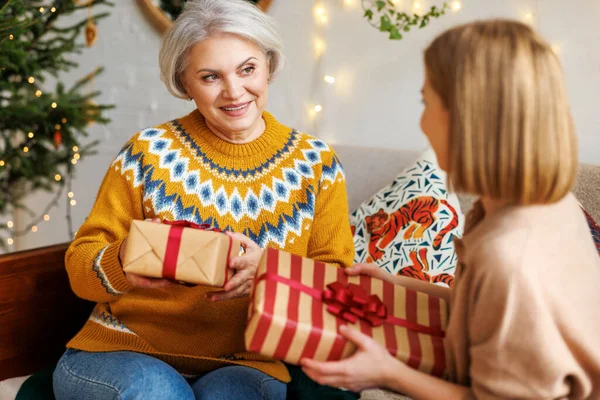 Lächelnde Seniorin tauscht am Weihnachtstag Weihnachtsgeschenke mit ihrer erwachsenen Tochter — Stockfoto