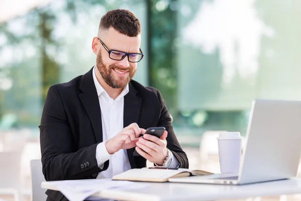 Modern akıllı telefonlu resmi kıyafetler içinde başarılı bir iş adamı açık havada çalışıyor. — Stok fotoğraf