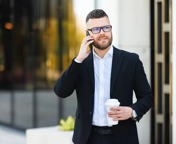 Giovane impiegato felice ufficio fuori parlando sul telefono cellulare con take away caffè in mano — Foto Stock