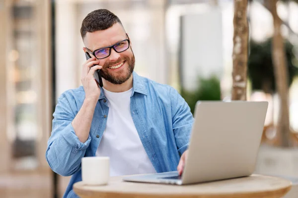 Glimlachende zakenman geniet van aangenaam gesprek op mobiele telefoon in outdoor cafe — Stockfoto